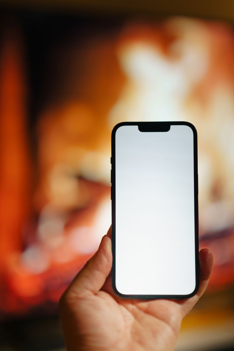 A smartphone held in front of a blurred fireplace, ideal for mockups.